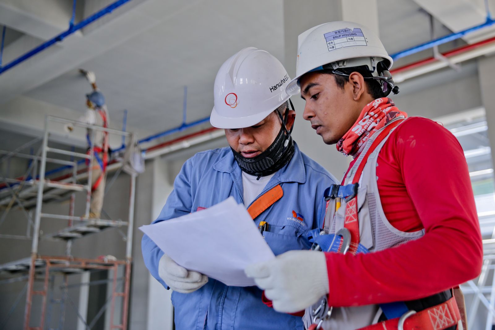 Two site workers reading a document together on a live construction site